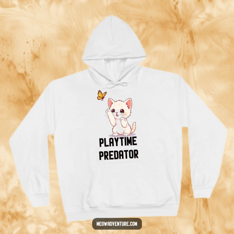 Funny curious kitten with paws raised, playfully batting at a butterfly, on a soft hoodie, capturing playful energy.