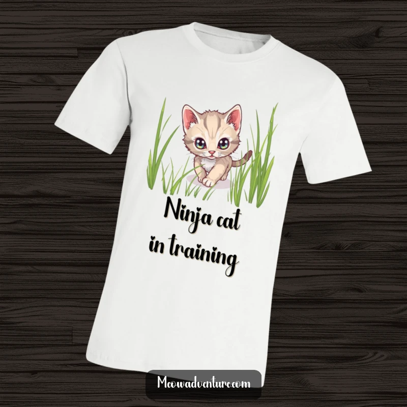 Funny t-shirt depicting a stealthy kitten with wide, alert eyes, tiptoeing through tall grass like a secret agent.