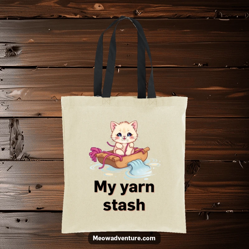 Funny fluffy kitten navigating a yarn stream on a yarn raft, printed on a practical tote bag.