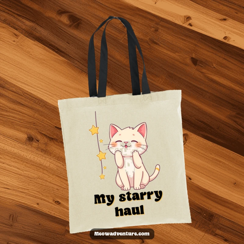 Funny tote bag showcasing a cat playfully batting at a string of stars, representing the pursuit of dreams and cosmic wonder.